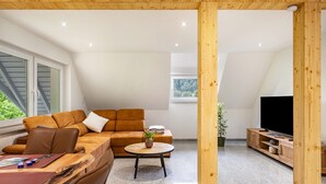 Un salon moderne avec un canapé d’angle, une table basse ronde et un téléviseur.