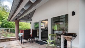 Une terrasse extérieure avec un barbecue, des chaises et une table.