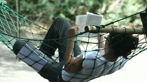 Eine Hängematte mit einer Person, die ein Buch liest, vor einer natürlichen Kulisse.