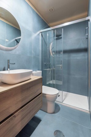 Une salle de bain moderne avec un grand lavabo ovale, des toilettes et une douche à parois de verre.