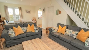 A living room with two grey sofas, wooden coffee table, and a staircase. - Sandy Cove (Chathill)
