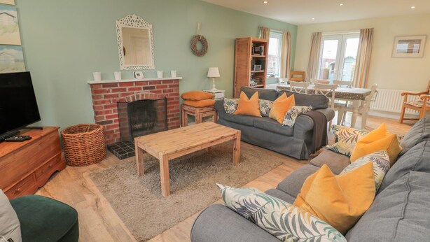 A cozy living room with a fireplace, a sofa set, a coffee table, and a television. - Sandy Cove (Chathill)