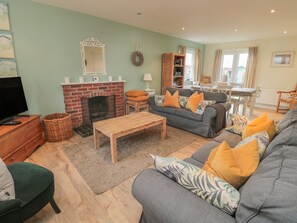 A cozy living room with a fireplace, a sofa set, a coffee table, and a television. - Sandy Cove (Chathill)