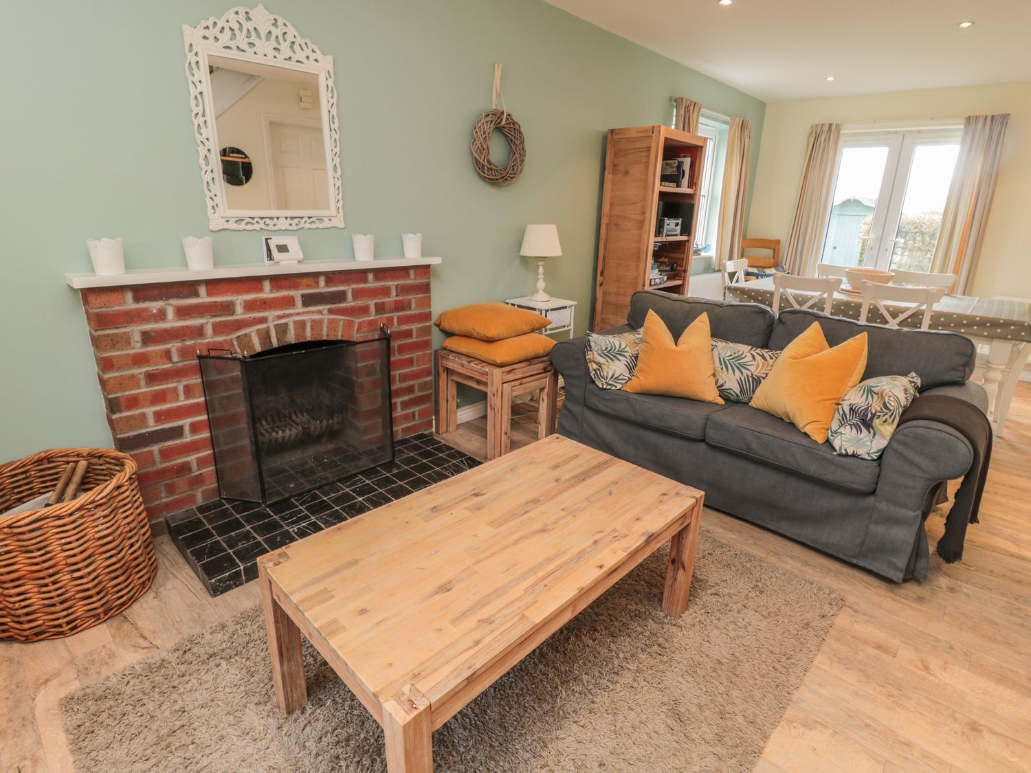 A cozy living room with a fireplace, a sofa with cushions, a wooden coffee table, and a wicker basket.