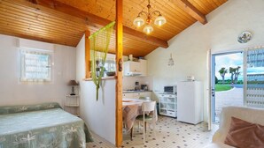 A cozy room with a bed, a dining table, a kitchen area, and a view of the outdoors. - Studio at the Farm – Peaceful Retreat for 2 Guests (Semussac)