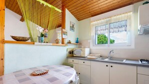 A kitchen with a table, cabinets, a microwave, and a sink. - Studio at the Farm – Peaceful Retreat for 2 Guests (Semussac)