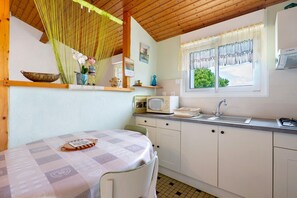 A kitchen with a table, cabinets, a microwave, and a sink. - Studio at the Farm – Peaceful Retreat for 2 Guests (Semussac)
