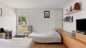 A bedroom with two beds, a TV, a bookshelf, and a window with a view of the outdoors. - Bed and Breakfast 'Chambre Laurier' with Shared Pool, Shared Garden and Wi-Fi (Le Controis-en-Sologne)