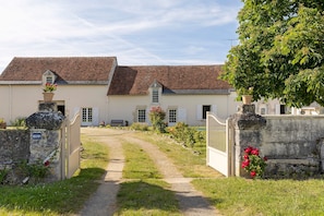 A traditional house with a gravel path leading to the entrance, a stone gate, and a flower pot on the left. - Bed and Breakfast 'Chambre Laurier' with Shared Pool, Shared Garden and Wi-Fi (Le Controis-en-Sologne)