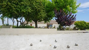 A courtyard with a concrete floor, several metallic balls, and a building with a tiled roof in the background. - Family Guest Room Anis (Semussac)