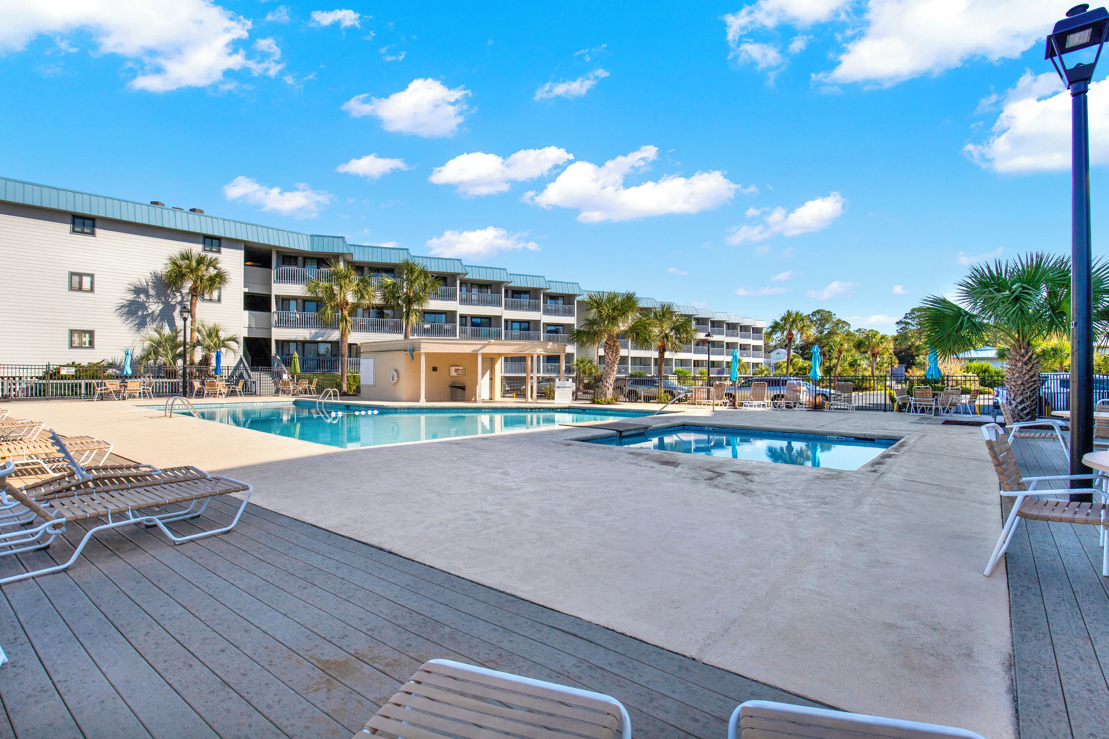 A hotel with a pool area, multiple balconies, and palm trees.