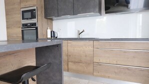 Una cucina moderna con mobili in legno, un lavello in acciaio inossidabile e un forno integrato.