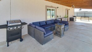 Une terrasse extérieure équipée d’un barbecue, d’un canapé d’angle et d’une petite table.