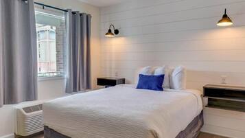 A hotel room with a bed, bedside tables, a heater, curtains, and a window with a view.