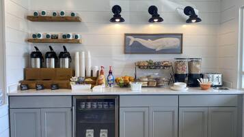 A kitchen with a white countertop, coffee machines, a refrigerator, and a microwave.