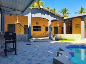 Une cour avec une piscine, un barbecue et un espace salon abrité.
