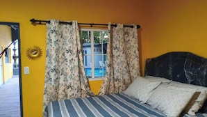Une chambre à coucher avec un lit, des rideaux, une fenêtre et une décoration représentant un soleil sur le mur.