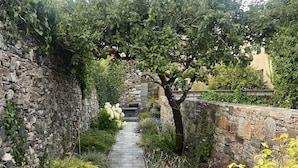 En sti af sten slynger sig gennem en have med forskellige planter og en fletstol.