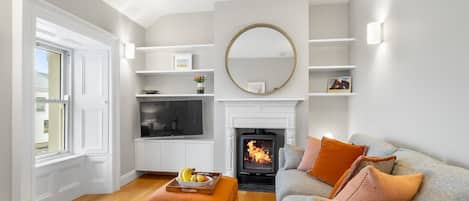 A living room with a fireplace, a television, and a sofa with cushions.