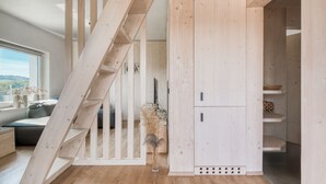A modern interior with a wooden staircase, built-in shelving, and a view of the outdoors. - Herb Haven Cottage With a View (Pesnica)
