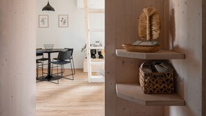A modern interior with a dining area, wooden shelves, and a basket with items. - Herb Haven Cottage With a View (Pesnica)