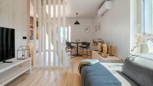 A modern living room with a sofa, TV, and dining area. - Herb Haven Cottage With a View (Pesnica)