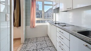 Una cuina moderna amb armaris blancs, un taulell de granit i una finestra amb vista a edificis.