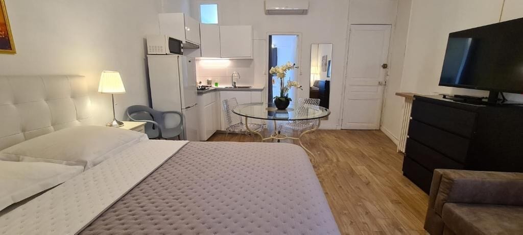 Une chambre d’hôtel équipée d’un lit, d’un bureau, d’une chaise, d’une télévision, d’une commode et d’une kitchenette.