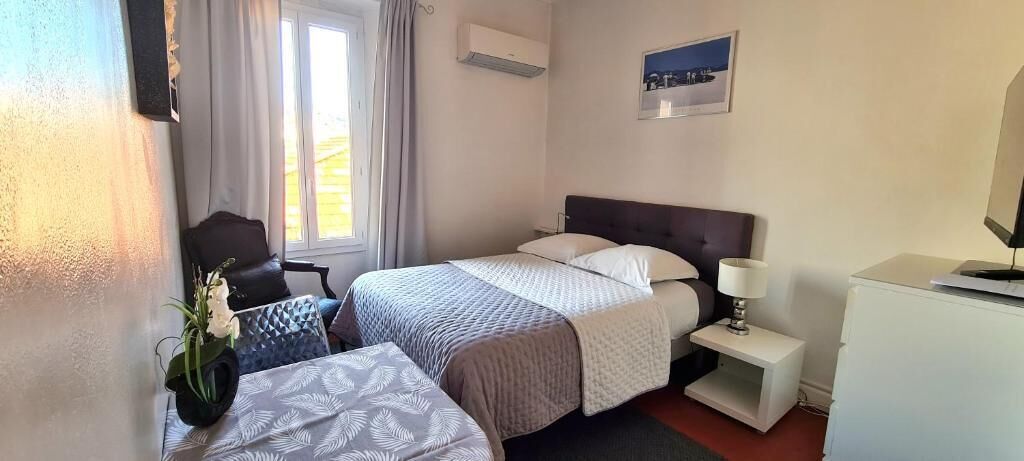 A hotel room with a bed, bedside table, lamp, and a small desk.