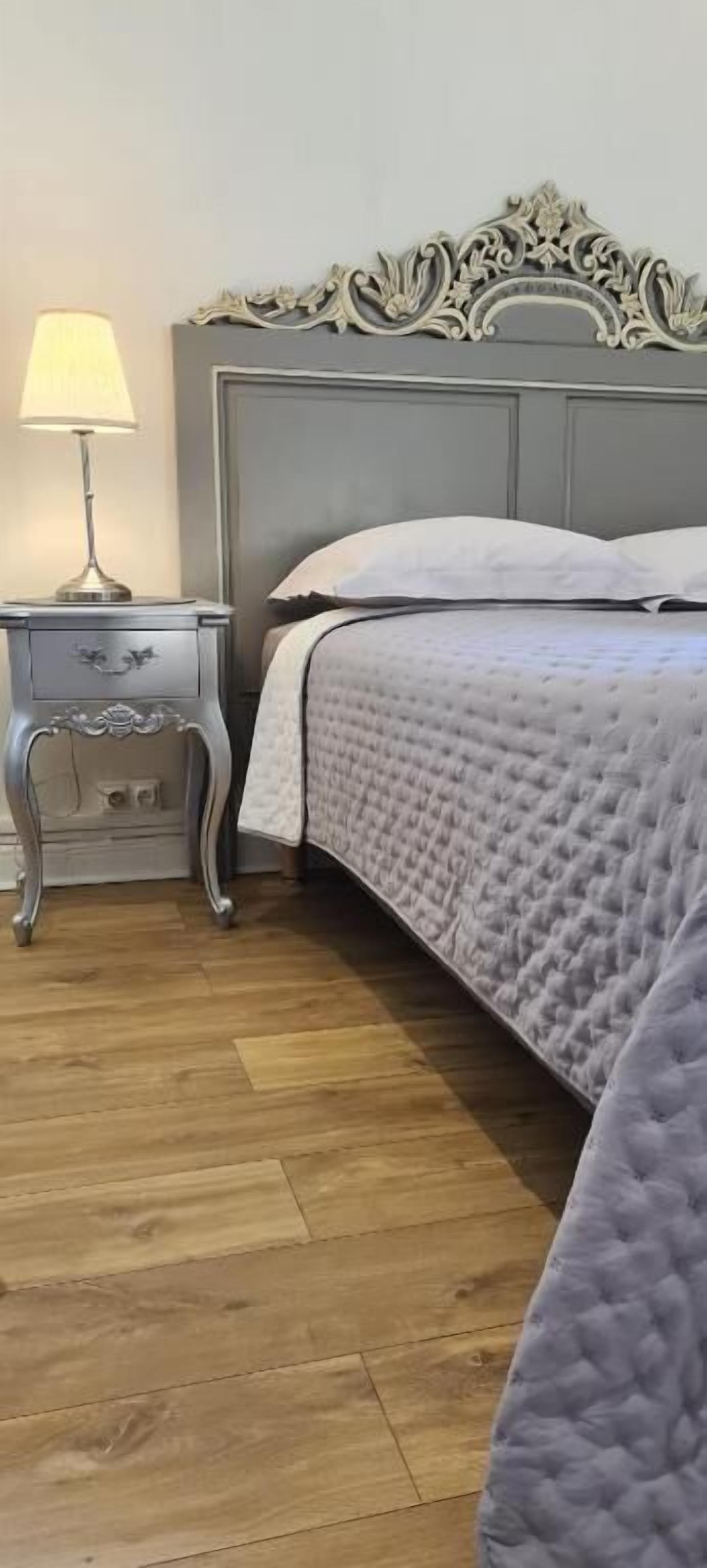 A bedroom with a bed, a nightstand, and a lamp.