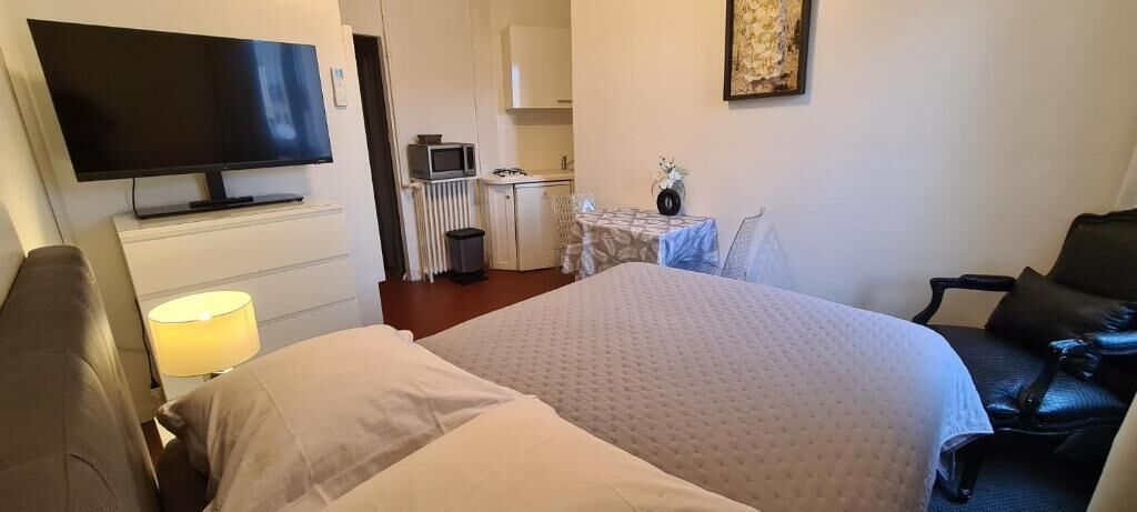 Habitación de hotel con cama, televisor, escritorio con silla y una pequeña cocina.