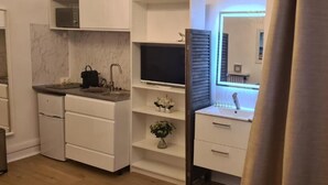 Μια σύγχρονη κουζίνα με λευκά ντουλάπια, εντοιχισμένο φούρνο μικροκυμάτων και πάγκο εργασίας με νεροχύτη.