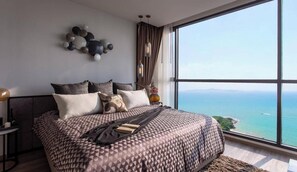 A modern bedroom with a large bed, a decorative wall piece, and a view of the sea. - Luxury 2 Bed Room Sea View - Excellent Location (Pattaya)