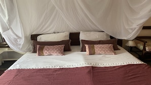 Un lit à baldaquin, deux tables de chevet et une petite table de nuit.