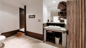 Une salle de bain comprenant des toilettes, un lavabo et un espace douche.