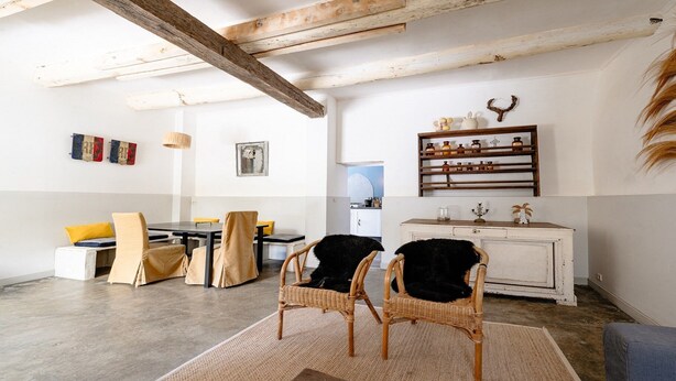 Une pièce comprenant une table à manger, des chaises, un buffet blanc et une étagère avec des bouteilles.