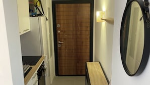 Een compacte keuken met een houten deur, een klein tafeltje en een spiegel.