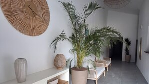 Een modern interieur met een witte consoles, een grote potplant en een zithoek met een bank en stoelen.