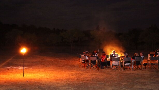 A group of people seated around a campfire at night. - Mahoora Tented Safari Camp Udawalawe (Udawalawa)
