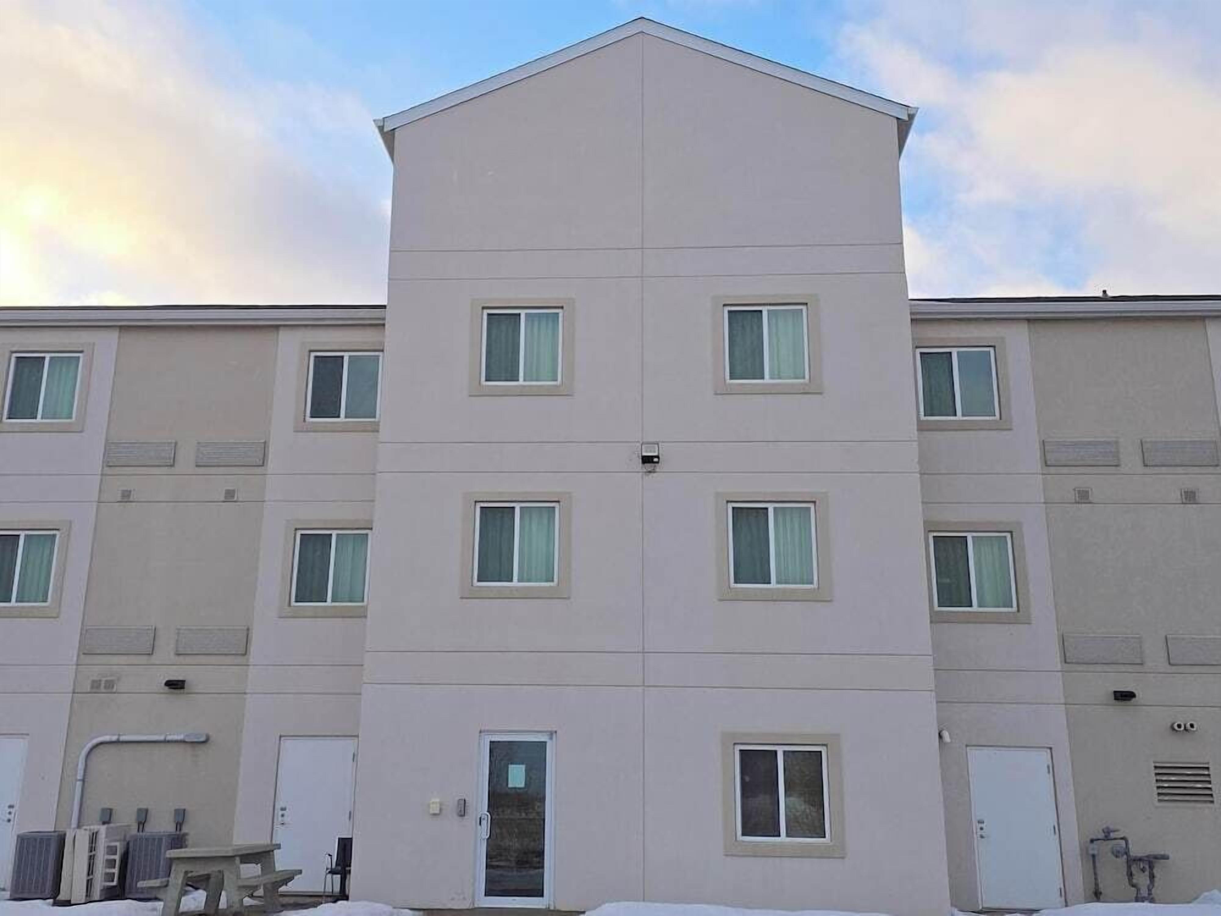 A multi-story building with a flat roof, several windows, and a door.
