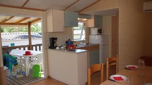 Eine kompakte Küche mit Essbereich, ausgestattet mit einem kleinen Tisch und Stühlen, einer Mikrowelle und einem Kühlschrank.