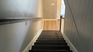 Una escalera de madera conduce a un rellano con una puerta.