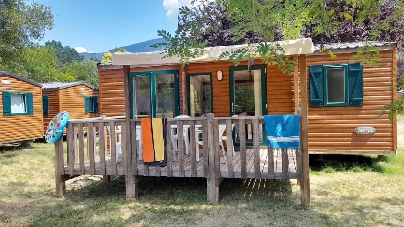 A wooden cabin with a deck, a door, and windows.