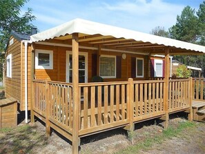 Una cabaña de madera con un porche cubierto y una terraza cercada.