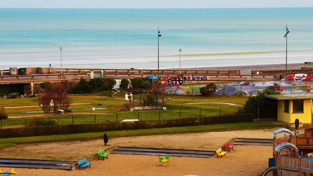A beach view with a flag, sandy area, and a building in the background. - Grand Hôtel du Casino de Dieppe (Dieppe)