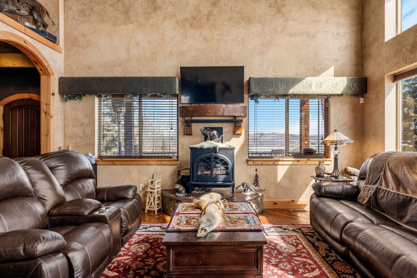 A cozy living room with leather sofas, a fireplace, and a dog.