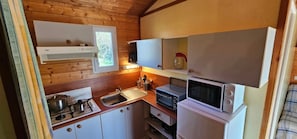 Eine kompakte Küche mit Gaskochfeld, Spüle, Mikrowelle und einem kleinen Kühlschrank.