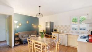 Una cucina compatta con tavolo e sedie, forno a microonde e frigorifero.