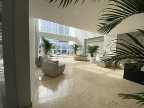A spacious lobby with a high ceiling, large windows, and a polished marble floor. There are several seating areas with modern furniture and potted plants. - Spacious and comfortable loft in Cartagena (Cartagena de Indias)
