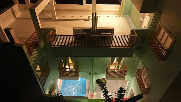 A multi-level hotel with a central swimming pool, balconies, and a view of the pool from the upper floors. - Green Resort Pondicherry (Vanur)